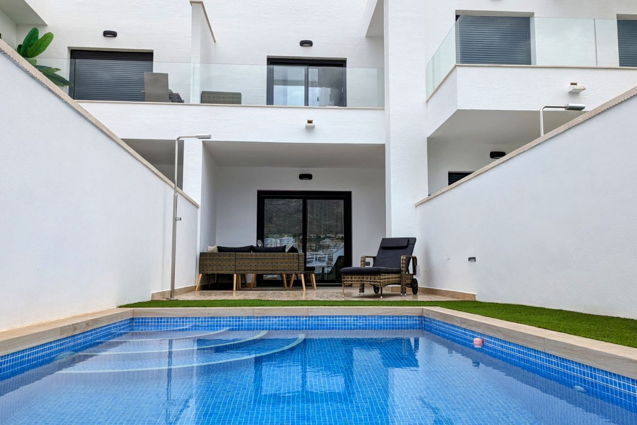 Un moderno edificio residencial con piscina, mobiliario de exterior y balcón.