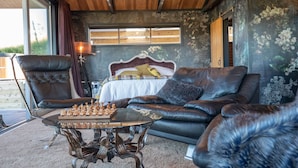 A bedroom with a large bed, a leather sofa, a glass coffee table, and a chessboard. - Holiday Bliss - Tirau, Piarere (Piarere)