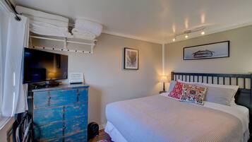 A bedroom with a bed, a dresser, a television, and a framed picture on the wall.