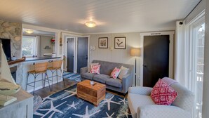 A cozy living room with a sofa, two chairs, a coffee table, and a kitchen area in the background. - The Akari Bungalow #5 (Long Beach)