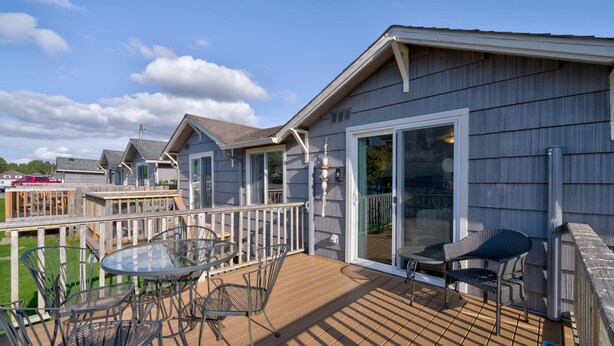 A deck with outdoor furniture, a glass door leading to a covered patio, and a view of neighboring houses. - The Akari Bungalow #5 (Long Beach)