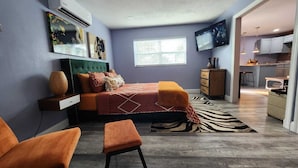 Un dormitorio moderno con cama, escritorio y televisor.
