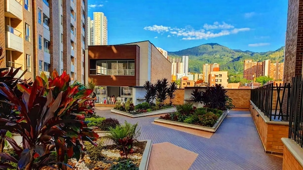A modern building with a flat roof and a courtyard with plants and a seating area.