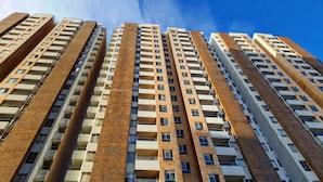 A high-rise residential building with multiple floors, each featuring balconies and a uniform brick facade.