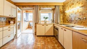 Eine Küche mit Holzschränken, einer gefliesten Spritzschutzwand und einem Fenster mit Vorhängen.