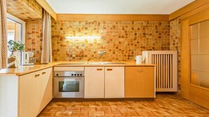 Eine kompakte Küche mit Fliesenrückwand, einem eingebauten Backofen und einem Spülbecken.