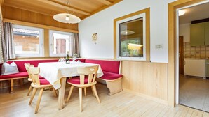 Ein Essbereich mit Holztisch, rot gepolstertem Sitzbänken und Holzsesseln.