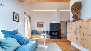 Una sala de estar moderna con un sofá azul, una mesita redonda y una chimenea.