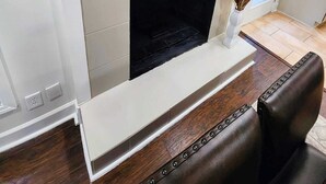 Un salon moderne avec une cheminée, un miroir rond et un coin salon doté d’un canapé en cuir.