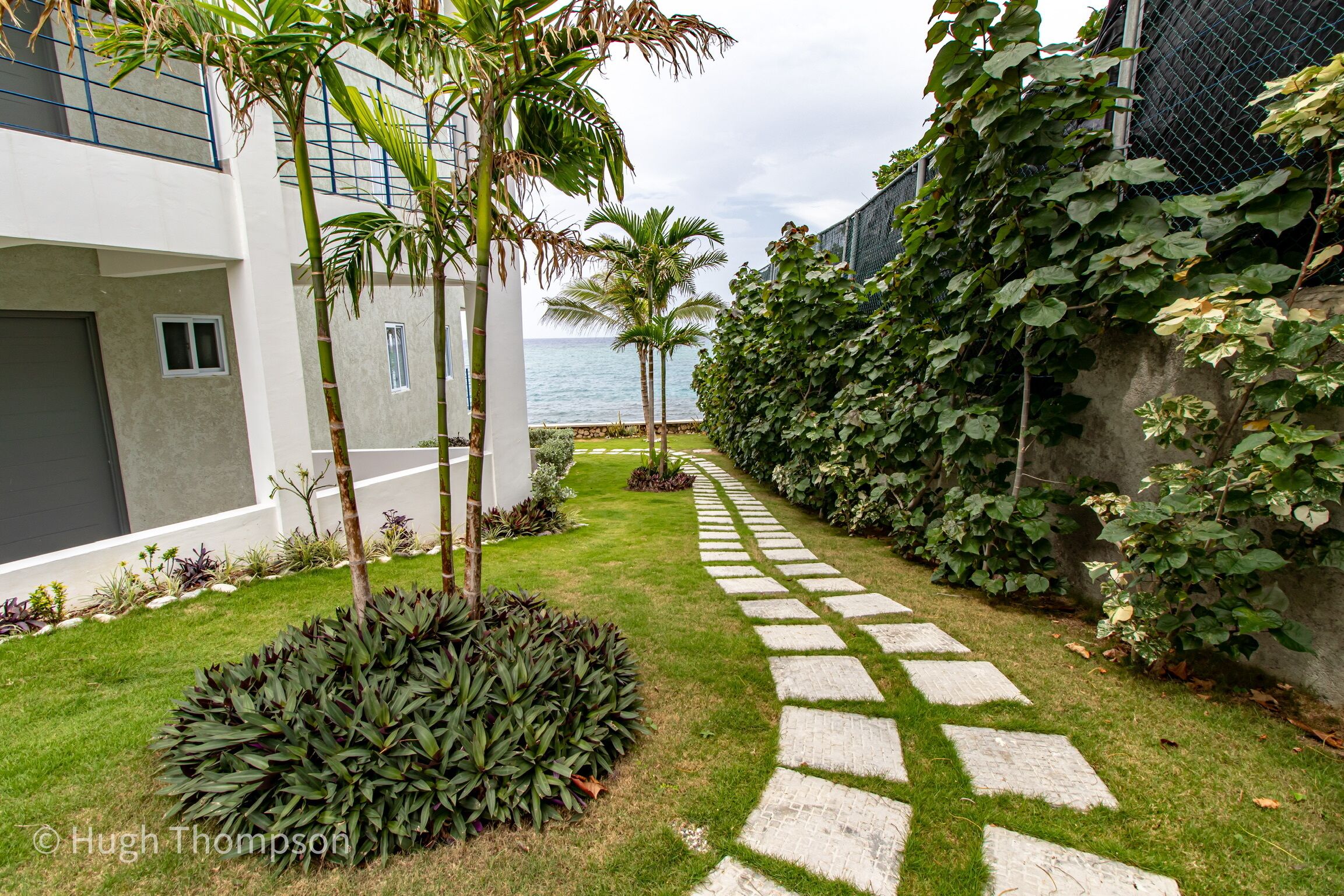 A pathway leading to a modern building with a view of the ocean.