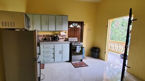 A compact kitchen with a refrigerator, stove, and cabinets.