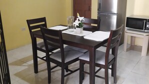 A dining area with a table, chairs, a refrigerator, and a microwave.
