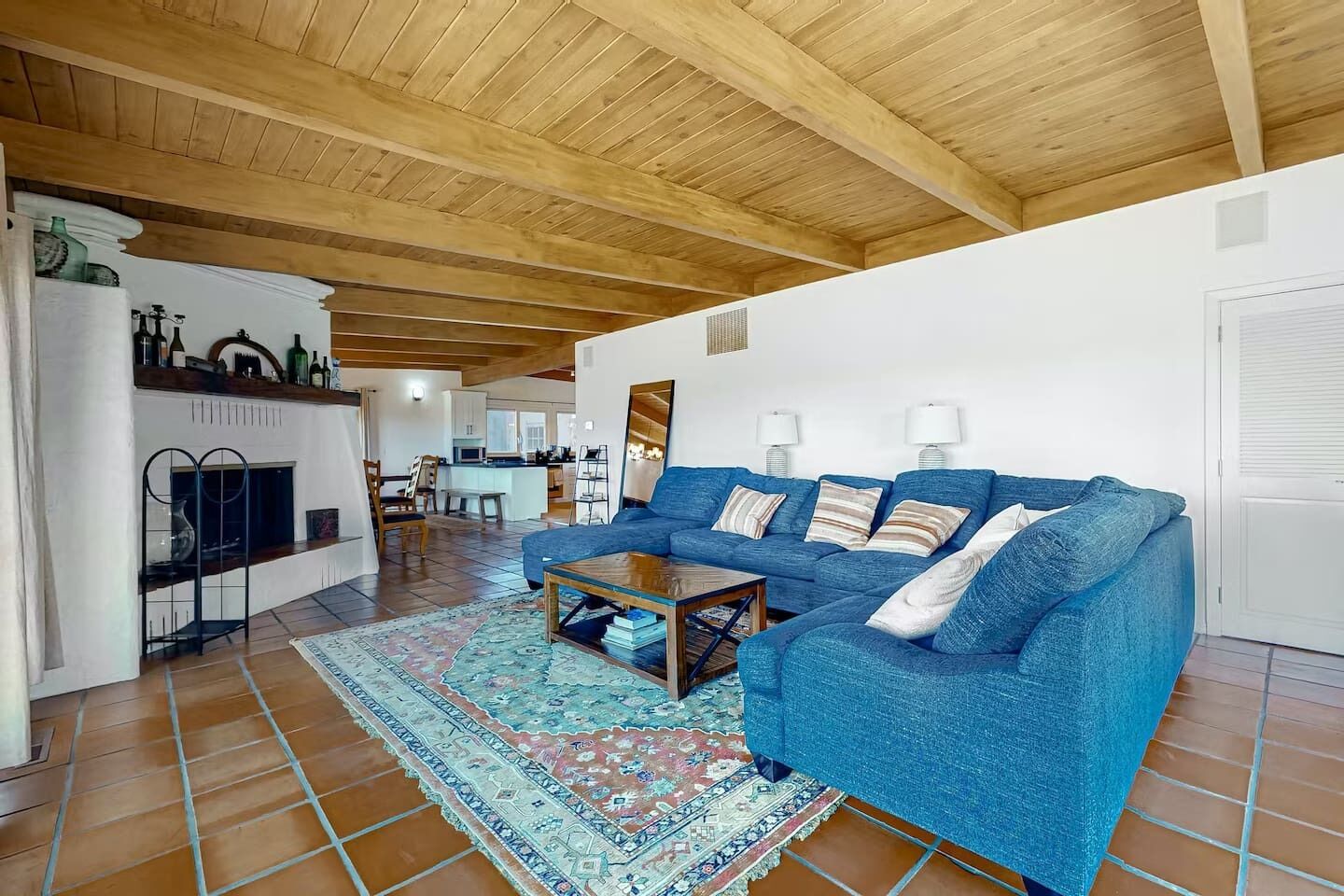 Inviting main living room with soaring wood-beamed ceilings, a classic adobe fireplace & plush sectional sofa the perfect spot to unwind after a day of wine tasting. Warm, character-filled & utterly relaxing.