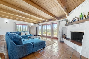 A spacious living area with a blue sofa, a fireplace, and a large window offering a view of the outdoors.