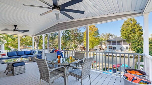 A covered deck with outdoor furniture, a table, and chairs. - Water Slide, Swim Mat, Kayaks! PET FRIENDLY - Retro Weeki Wachee River! (Weeki Wachee)