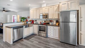 A modern kitchen with white cabinetry, stainless steel appliances, and a central island. - Water Slide, Swim Mat, Kayaks! PET FRIENDLY - Retro Weeki Wachee River! (Weeki Wachee)