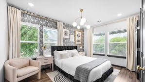 Une chambre à coucher avec un lit, des tables de chevet, une chaise et une fenêtre avec des stores.