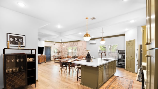 Une cuisine moderne dotée d’un îlot central, de planchers en bois et de luminaires suspendus.
