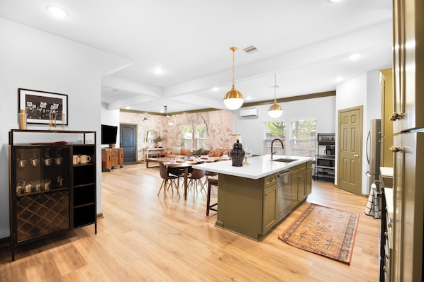 A modern kitchen with a central island, wooden flooring, and pendant lighting.