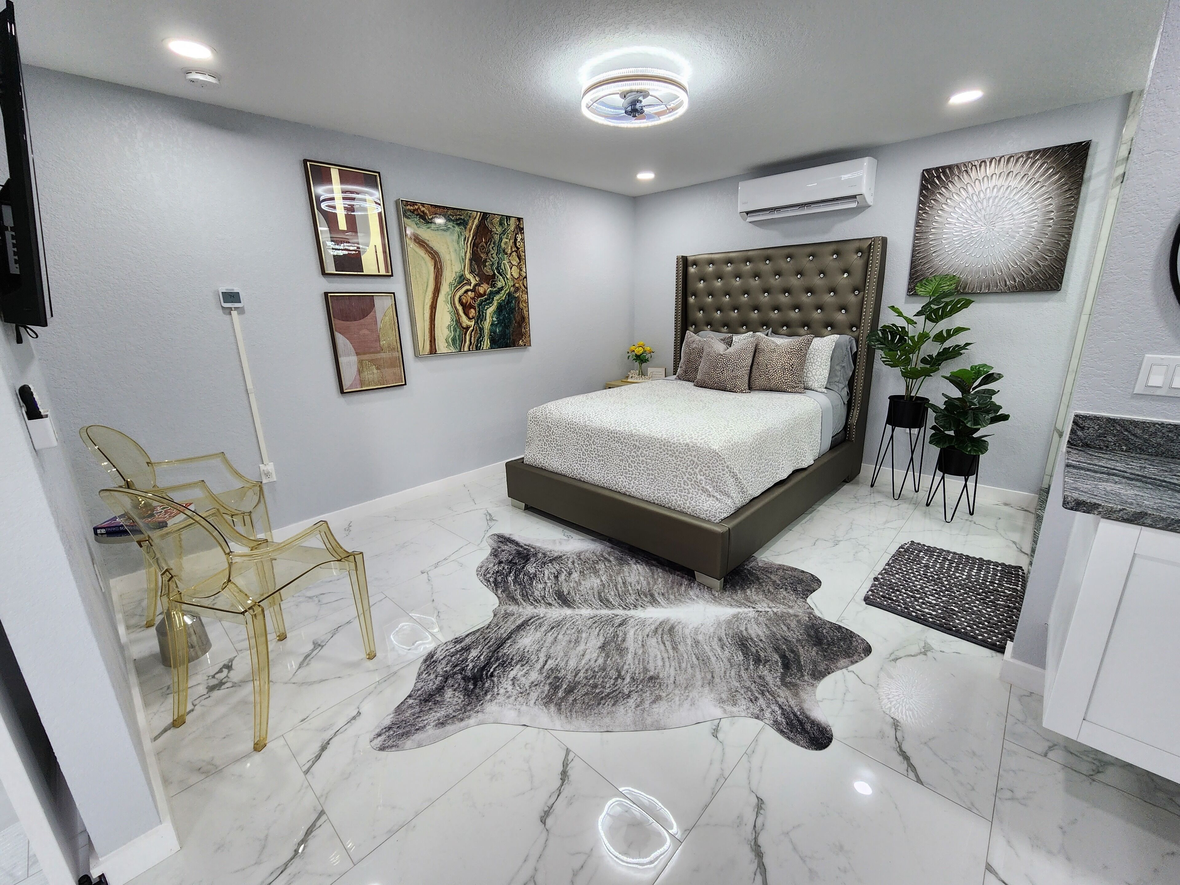 A modern bedroom with a tufted headboard, a large bed, a glass chair, and a rug.