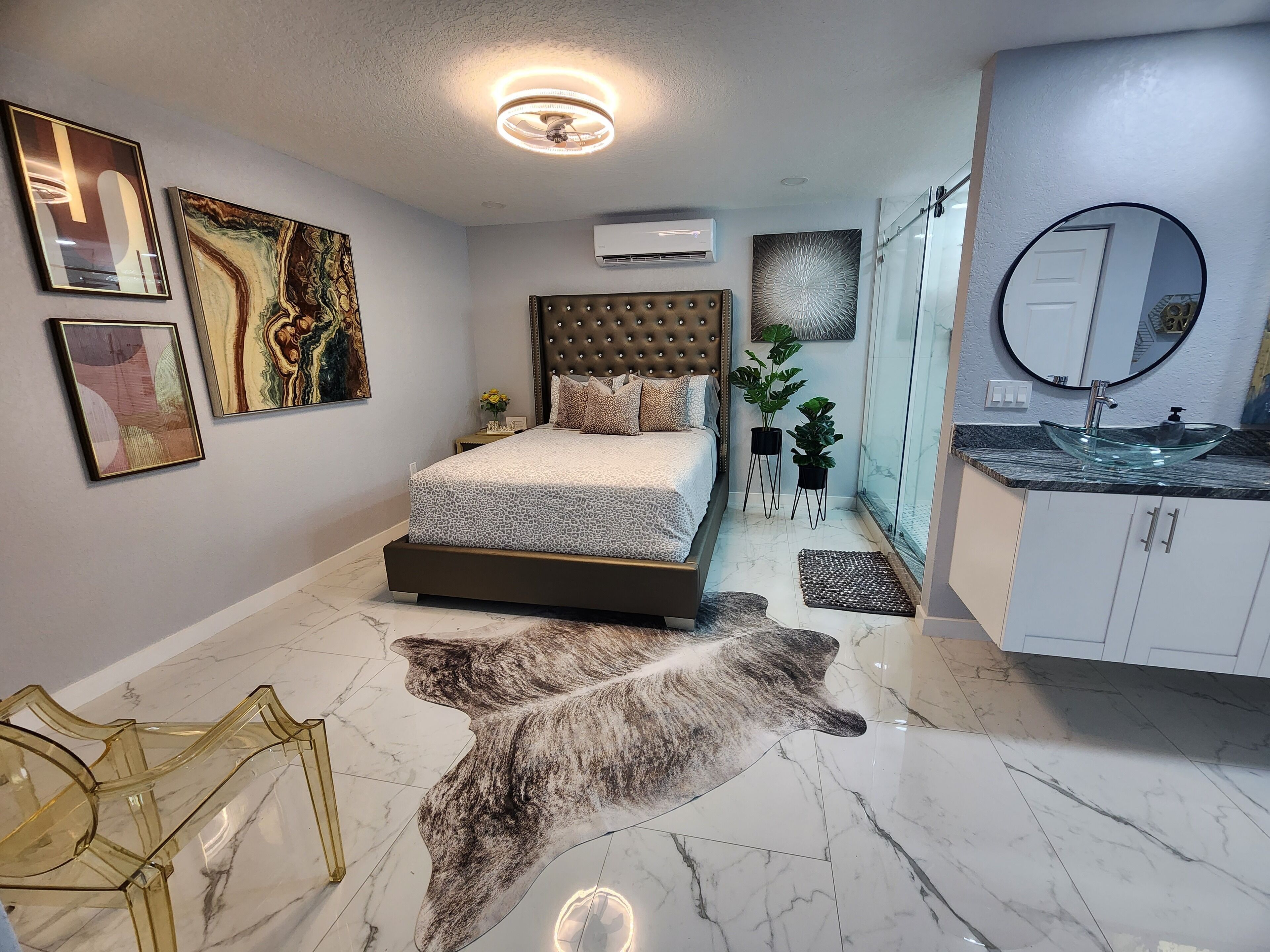 A modern bedroom with a large bed, a glass sink, and artwork on the walls.