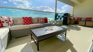 A spacious balcony with a view of the ocean, wicker furniture, and a ceiling fan. - Spacious Apto With Spectacular Views Of The Beach (Guayacanes)