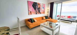 Una sala de estar con un sofá, una mesa de centro de vidrio y un cuadro en la pared.