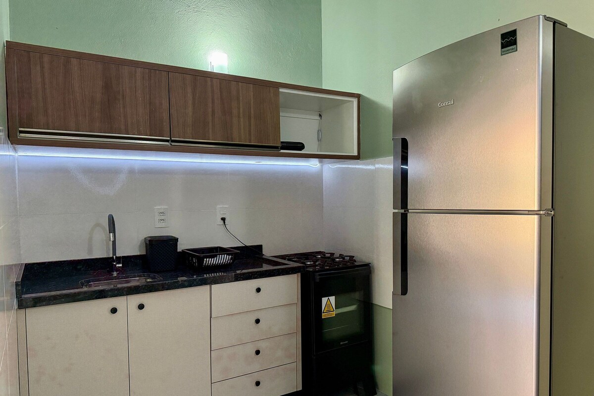 A kitchen with a refrigerator, stove, and cabinets.