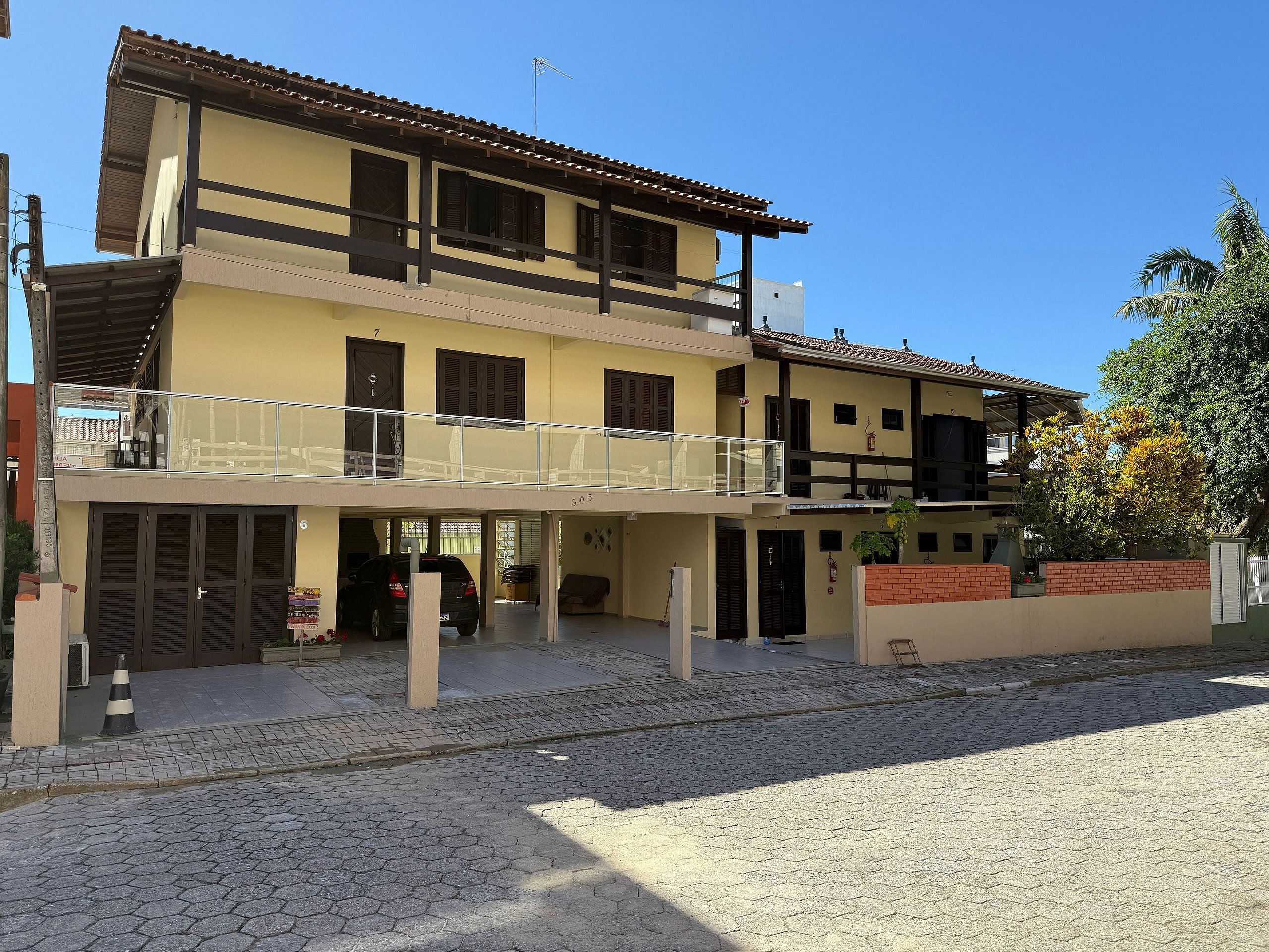 Un edificio de dos pisos con un balcón, un garaje y un muro de ladrillo.