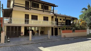 A two-story building with a balcony, a garage, and a brick wall. - Ancoragem (Bombinhas)