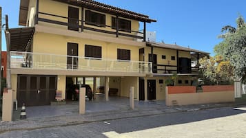 Un edificio de dos pisos con un balcón, un garaje y un muro de ladrillo.
