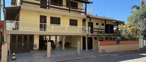 A two-story building with a balcony, a garage, and a brick wall.