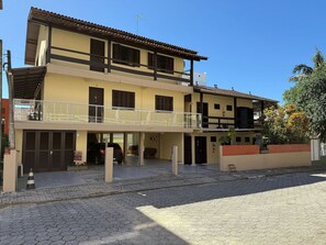 Un edificio de dos pisos con un balcón, un garaje y un muro de ladrillo.