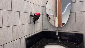 A bathroom with a black countertop sink, a mirror, and a hairdryer mounted on the wall. - Ancoragem (Bombinhas)