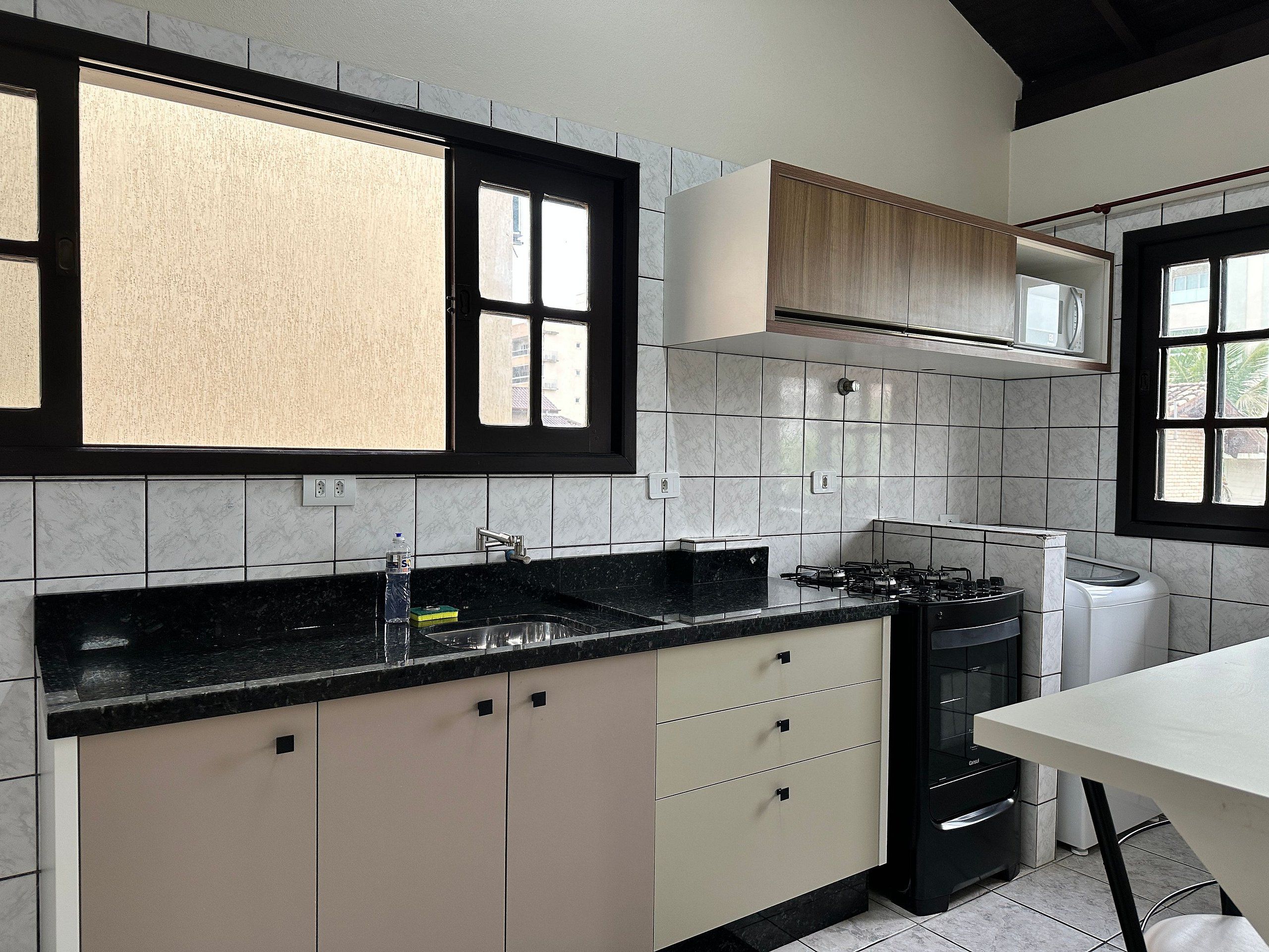 A modern kitchen with a black countertop, white cabinets, and a window with a view of buildings.