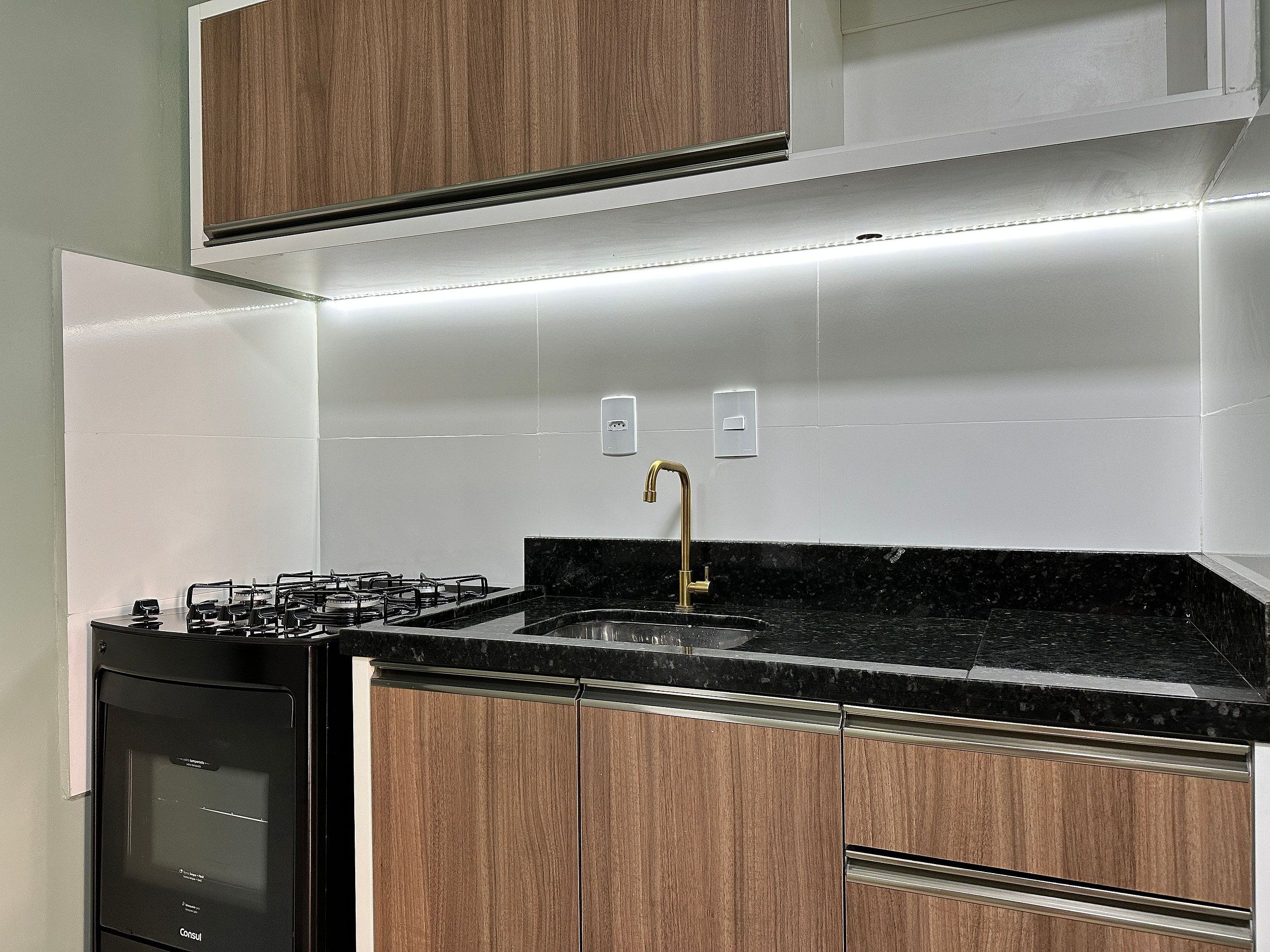 Una cocina moderna con estufa a gas, encimera negra y armarios de madera.