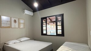 A bedroom with a bed, a window with a view of buildings, and an air conditioning unit. - Ancoragem (Bombinhas)