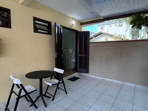A balcony with a table and chairs, a door, and a view of the street.