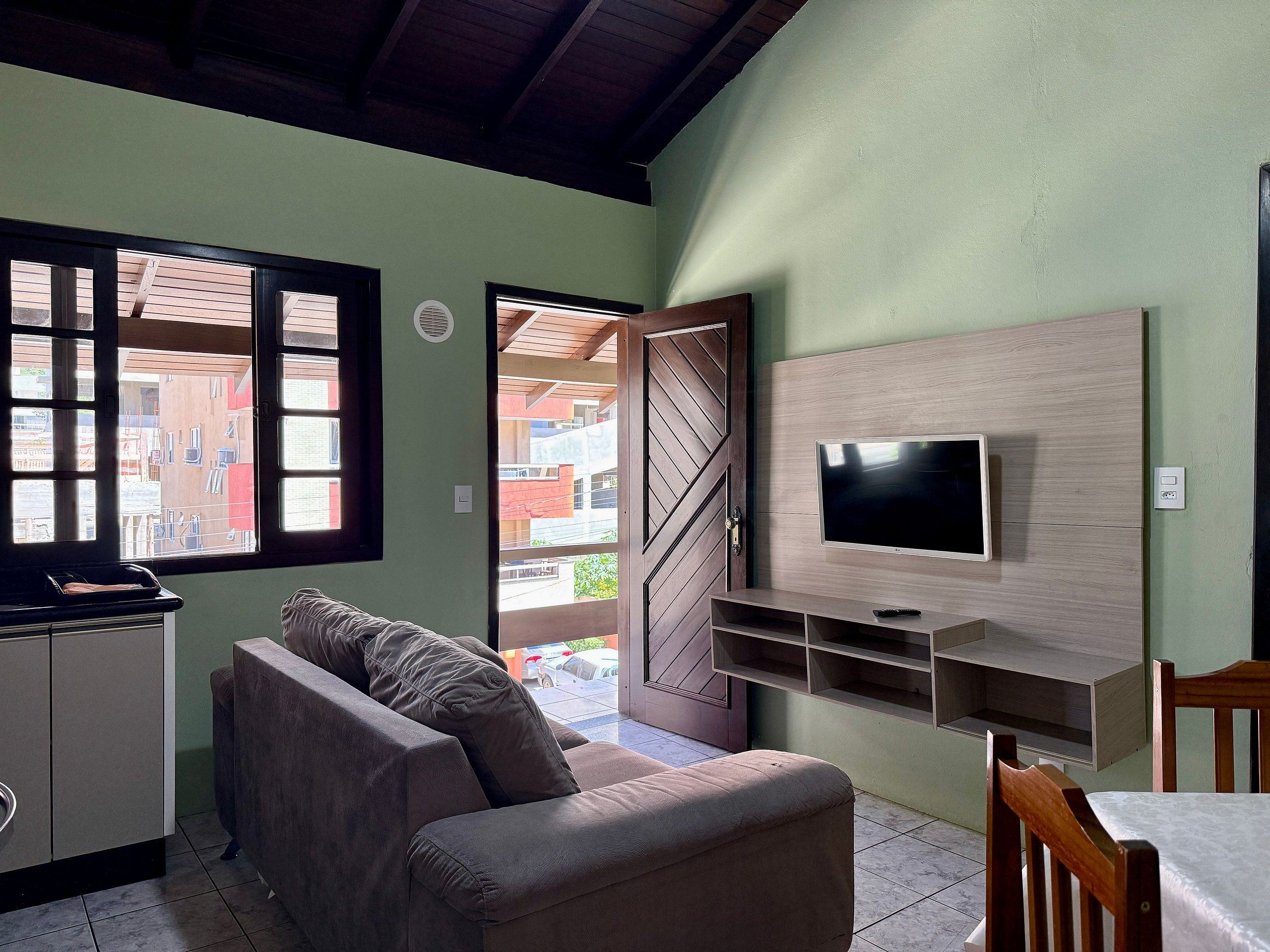 A living room with a sofa, TV, and a dining area.
