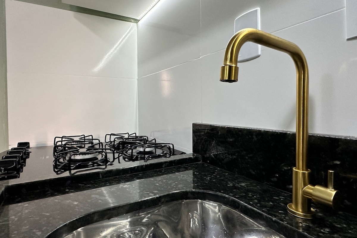 A kitchen with a gas stove, a sink, and a gold faucet.