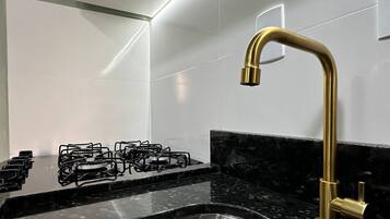 Een keuken met een gasfornuis, een spoelbak en een gouden kraan.