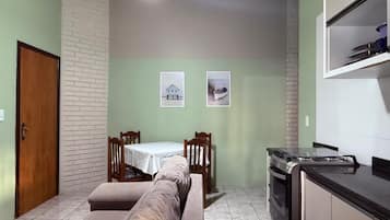 A compact living space with a kitchenette, a dining area with a table and chairs, and a sofa.