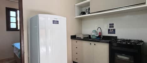 A compact kitchen with a refrigerator, stove, and sink.