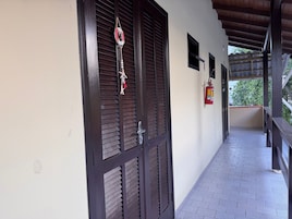 Un corridoio con una porta in legno, un estintore e una piccola finestra.