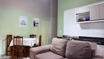 A compact living space with a dining area, a kitchenette, and a sofa.