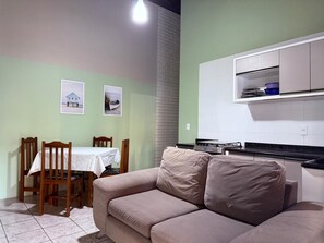 A compact living space with a dining area, a kitchenette, and a sofa. - Ancoragem (Bombinhas)