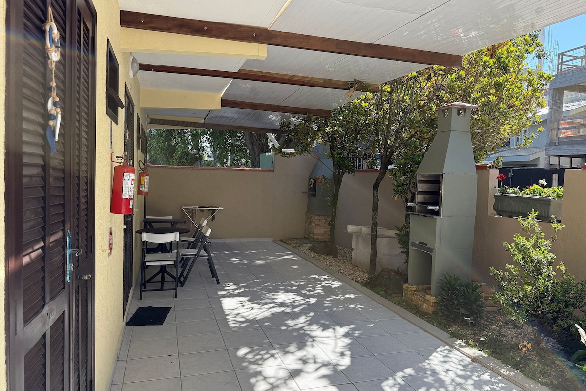 A covered patio area with a barbecue grill, a fire extinguisher, and outdoor seating.