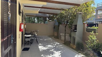 A covered patio area with a barbecue grill, a fire extinguisher, and outdoor seating.