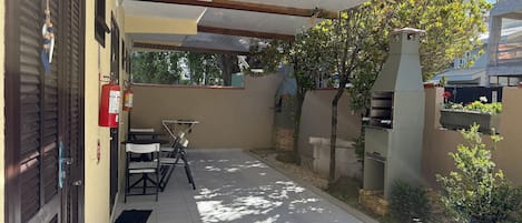 Un'area patio coperta con una griglia per barbecue, un estintore e mobili da esterno.