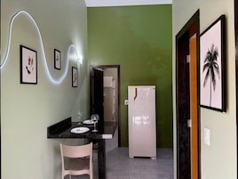 Una cucina compatta con angolo pranzo, frigorifero e una lampada a parete.